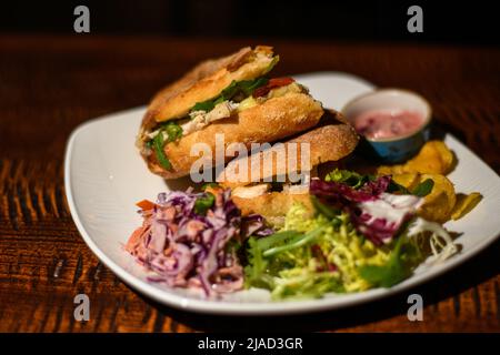 Primo piano di panini con pollo, brie e insalata con insalata di coleslaw, insalata mista verde e crocchette Foto Stock