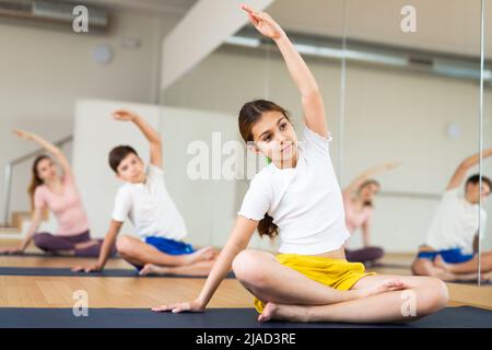 Ragazza che pratica yoga in studio con la famiglia Foto Stock