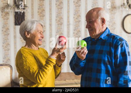 bella coppia pensionato che tiene le mele nel soggiorno sano mangiare concetto medio shot indoor. Foto di alta qualità Foto Stock