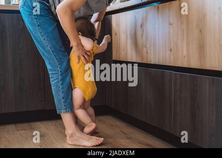 Madre che raccoglie il bambino arrabbiato in piedi ai suoi piedi. Madre e suo bambino. Foto Stock