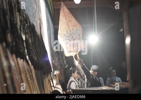 Un uomo chiamato Dhalang, esegue Giavanese Shadow Puppet o Wayang Kulit Foto Stock