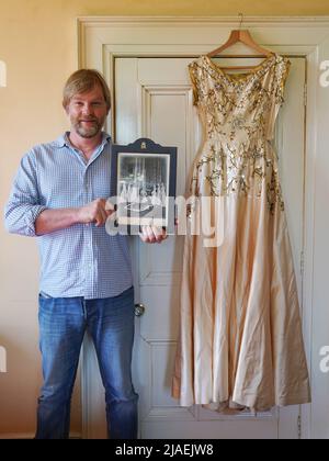 Rory Campbell, nella sua casa a Randalstown, Co. Antrim, tenendo una fotografia di sua madre Lady Moyra Campbell (a sinistra) con la regina Elisabetta II il giorno dell'incoronazione, insieme al vestito Lady Campbell indossava come una cameriera d'onore all'incoronazione della regina nel 1952. L'abito sarà esposto come parte di una speciale mostra giubilare di diamanti al Castello di Enniskillen. Data immagine: Giovedì 26 maggio 2022. Foto Stock