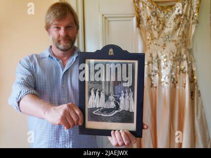 Rory Campbell, nella sua casa a Randalstown, Co. Antrim, tenendo una fotografia di sua madre Lady Moyra Campbell (a sinistra) con la regina Elisabetta II il giorno dell'incoronazione, insieme al vestito Lady Campbell indossava come una cameriera d'onore all'incoronazione della regina nel 1952. L'abito sarà esposto come parte di una speciale mostra giubilare di diamanti al Castello di Enniskillen. Data immagine: Giovedì 26 maggio 2022. Foto Stock