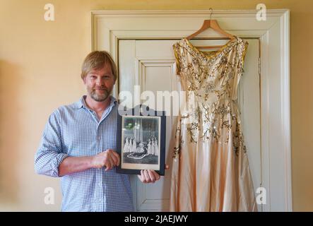 Rory Campbell, nella sua casa a Randalstown, Co. Antrim, tenendo una fotografia di sua madre Lady Moyra Campbell (a sinistra) con la regina Elisabetta II il giorno dell'incoronazione, insieme al vestito Lady Campbell indossava come una cameriera d'onore all'incoronazione della regina nel 1952. L'abito sarà esposto come parte di una speciale mostra giubilare di diamanti al Castello di Enniskillen. Data immagine: Giovedì 26 maggio 2022. Foto Stock