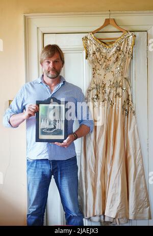 Rory Campbell, nella sua casa a Randalstown, Co. Antrim, tenendo una fotografia di sua madre Lady Moyra Campbell (a sinistra) con la regina Elisabetta II il giorno dell'incoronazione, insieme al vestito Lady Campbell indossava come una cameriera d'onore all'incoronazione della regina nel 1952. L'abito sarà esposto come parte di una speciale mostra giubilare di diamanti al Castello di Enniskillen. Data immagine: Giovedì 26 maggio 2022. Foto Stock