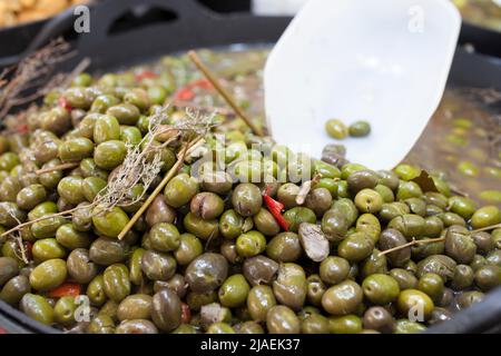 Olive marinate tritate verdi. Delizioso cestino di plastica con spuntini sottaceto Foto Stock