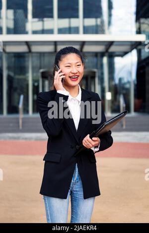donna d'affari che parla per telefono davanti all'ufficio Foto Stock