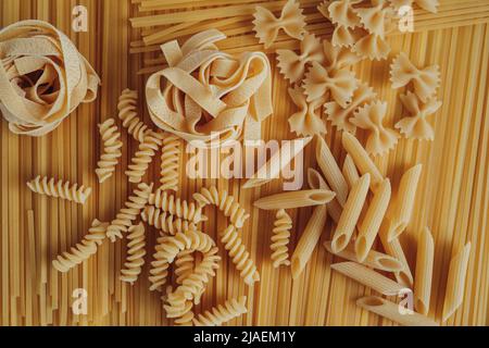 Diversi tipi di pasta disposti sullo sfondo degli spaghetti Foto Stock