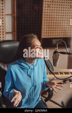 La giovane anchorwoman africana esegue registrazioni audio, parla in microfono in studio di registrazione o trasmissione musicale Foto Stock