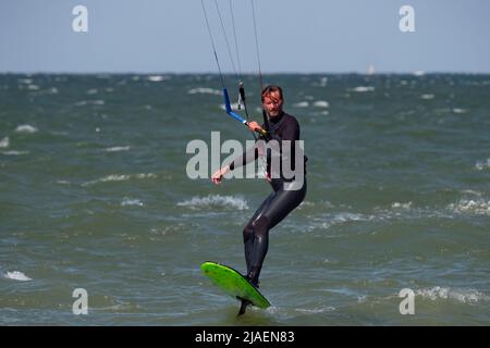Maschio Kite Surfer lamina con barba e capelli lunghi sul mare. Foto Stock