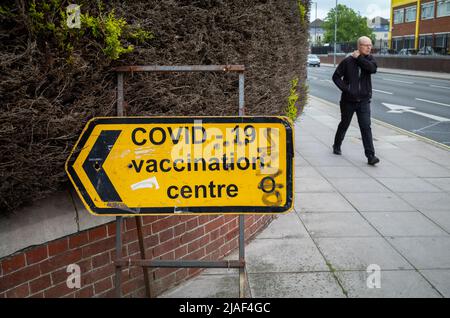 Un uomo cammina oltre un cartello per un centro di vaccinazione COVID-19 a Portsmouth, Hampshire, Inghilterra. Foto Stock