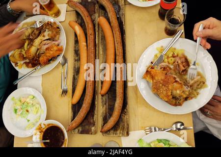 Primo piano salsicce tedesche e zoccoli di maiale fritti con birra ghiacciata, insalata di coleslaw e salse da immersione assortite Foto Stock