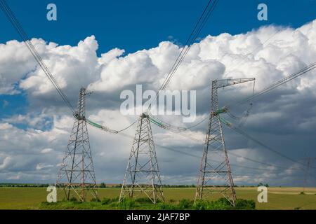 Linea di alimentazione ad alta tensione piloni contro il cielo blu con nuvole. Fornitura e distribuzione di energia elettrica Foto Stock