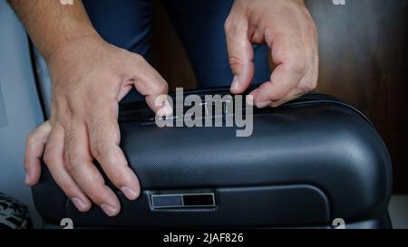 vista posteriore di un uomo d'affari irriconoscibile che sta per lasciare la casa con una valigia, egli porta una valigia su ruote Foto Stock