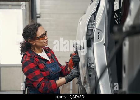 Meccanico auto femminile che ripara l'auto al negozio di riparazione auto Foto Stock