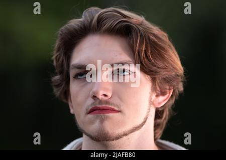 Ritratto di giovane uomo con guardato e trucco su. Maschio transgender con rossetto rosso e liner sugli occhi Foto Stock