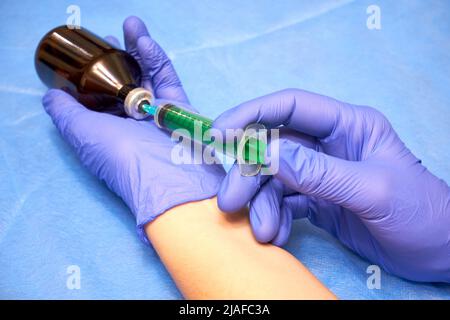 Mani di un medico in guanti che riempiono una siringa Foto Stock