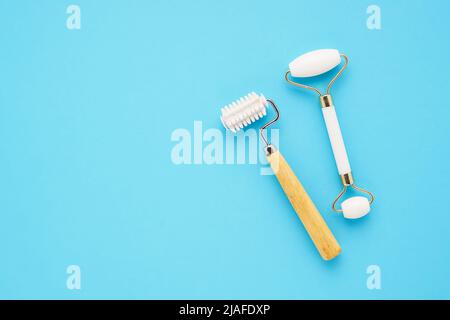 Due diversi rulli massaggianti per il viso su sfondo blu. Cura di se stessi, concetto di cura della pelle. Spazio di copia per il testo, vista dall'alto Foto Stock