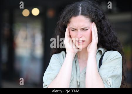 Stressata donna che soffre emicrania lamentarsi per strada Foto Stock