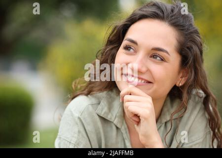 La donna pensiva guarda il lato che si chiede seduto in un parco Foto Stock