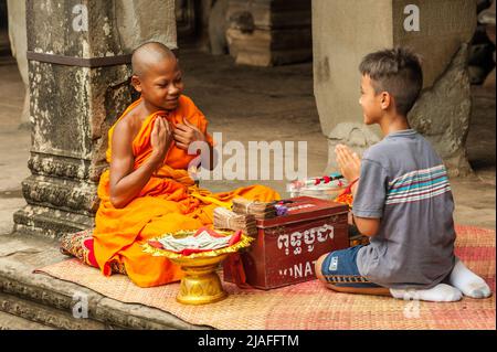 Il ragazzo misto di razza di 9 anni paga rispetto ad un giovane monaco buddista (circa la stessa età di lui), il monaco novizio è onorato. Angkor Wat, Provincia di Siem Reap, Cambogia. Credit: Kraig Lieb Foto Stock