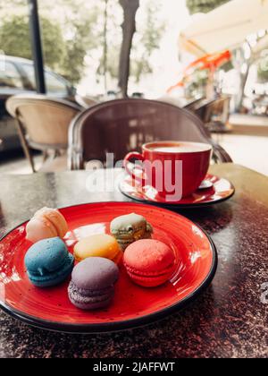 Un'immagine ravvicinata di colorate torte di macaron e tazza di caffè scattate in un caffè di strada Foto Stock