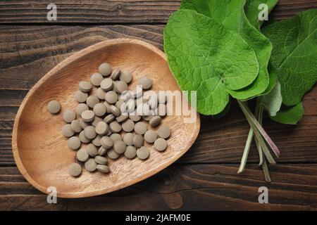 Foglie di burdock e pillole con estratto di lappa di arczio - nome latino per Burdock. Vista dall'alto. Foto Stock