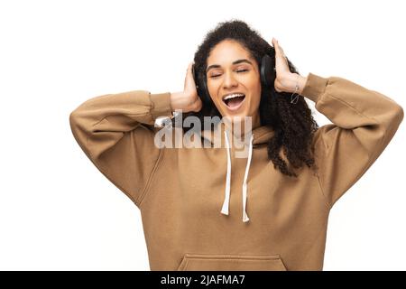 Adorabile donna con cappuccio casual che utilizza auricolari wireless per ascoltare musica, adolescente in cuffie godere i brani preferiti isolato su sfondo bianco Foto Stock