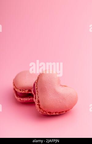 A forma di cuore Dolce macaron su sfondo rosa. Foto Stock