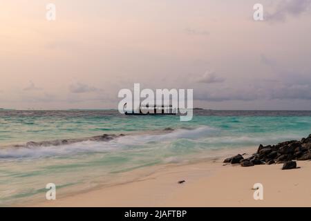 Vista di un tradizionale dhoni Maldiviano ancorato al largo della costa nelle belle acque turchesi blu dell'oceano nelle Maldive. Foto Stock