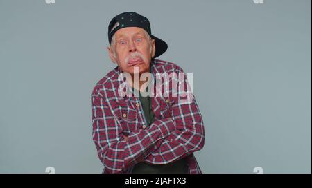L'uomo divertente che mostra la lingua che fa i volti alla macchina fotografica, che imbraccia intorno, che scherza, che si aggrappa con il volto sciocco Foto Stock