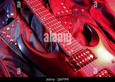Chitarra elettrica su una giacca in pelle illuminata in rosso Foto Stock