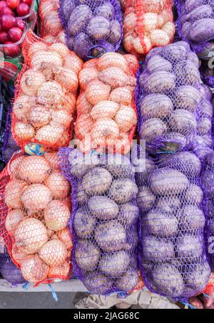 Cipolle e patate fresche e biologiche confezionate in sacchi in vendita sul mercato Foto Stock