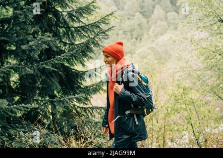 Donna escursionista cammina attraverso la foresta in montagna Foto Stock