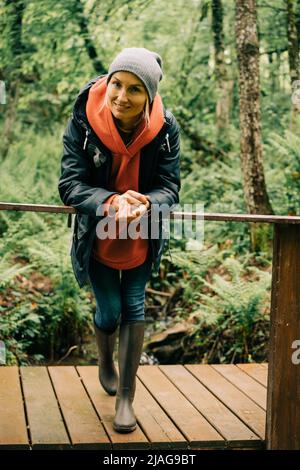 Ritratto di una donna allegra escursionista appoggiato sulla ringhiera di un ponte di legno Foto Stock