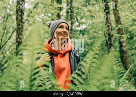 Ritratto di una giovane donna wellness escursionista in un thicket di felci in una foresta di primavera Foto Stock