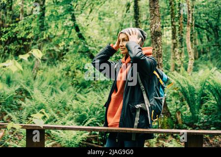 Giovane donna caucasica in un impermeabile e un cappello nel bosco Foto Stock