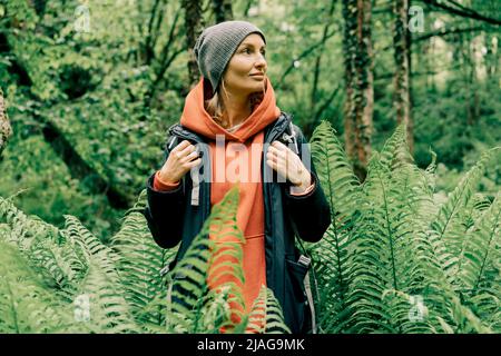 Giovane donna caucasica in un impermeabile e un cappello nel bosco Foto Stock