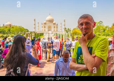 Il viaggiatore e il turista pone di fronte al famoso Taj Mahal in Agra India Mogul marmo mausoleo e panorama del famoso 17th secolo simmetrico g Foto Stock