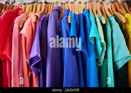 Abbigliamento colorato sostenibile Hanging on Rail in Charity o Thrift Store vendere la moda sostenibile Foto Stock