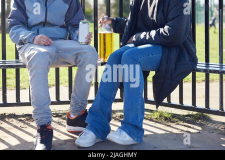 Primo piano di adolescenti minorenni che bevono alcol nel Parco Foto Stock