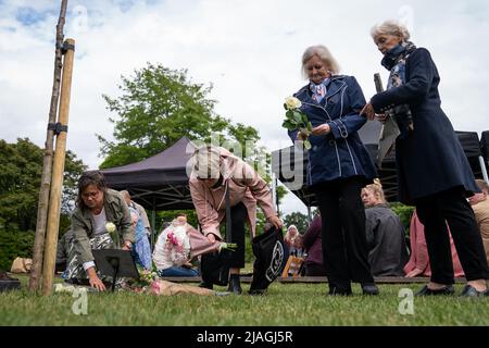 I fiori vengono impressi durante una cerimonia di piantagione di alberi e di inaugurazione della placca per il 50th° anniversario della tragedia di Battersea Park Big Dipper, a Battersea Park, nel sud-ovest di Londra. Cinque bambini sono stati uccisi e altri 13 feriti il 30 1972 maggio, quando le montagne russe Big Dipper sono crollate. Data foto: Lunedì 30 maggio 2022. Foto Stock