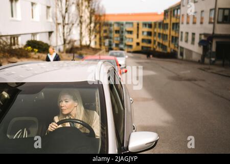 Donna d'affari seduta in auto vista attraverso il parabrezza Foto Stock