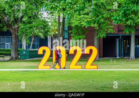 NEW ORLEANS, LA, USA - 12 MAGGIO 2022: Studente universitario nero che passa di fronte a 2022 al campus della Loyola University durante la settimana di laurea Foto Stock