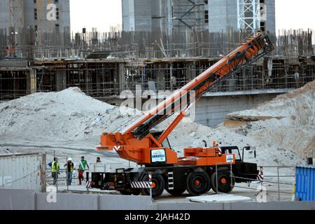 Giza, Egitto, maggio 23 2022: Una gru montata su camion presso il cantiere di nuovi edifici della città di Zed Z con lavoratori intorno, Sheikh Zayed città, acr Foto Stock