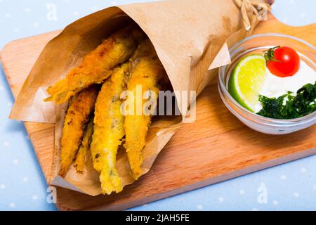 Acciughe fritte in padella con salsa cremosa al formaggio, verdure Foto Stock