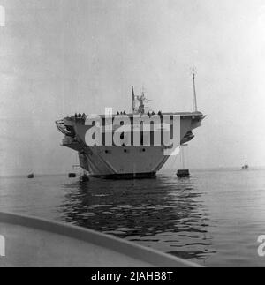 1950s, vista posteriore storica della nave Royal Navy, della portaerei leggeri, HMS Centaur, ormeggiata, possibilmente a Devonport, Plymouth, Inghilterra, Regno Unito. Foto Stock