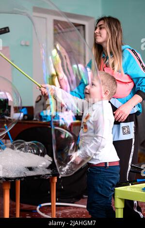 Dolyna, Ucraina 28 maggio 2021: Animatori e bolle di sapone per una vacanza dei bambini, un ragazzo che fa una bolla grande da solo, uno spettacolo divertente e divertente. Foto Stock