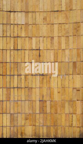Muro fatto di piastrelle o blocchi di colore giallo e arancione intemperie e sporchi. Vista frontale. Sfondo testurizzato full frame ad alta risoluzione. Spazio di copia. Foto Stock