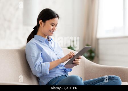 Felice donna cinese che si diverti con la nuova app sul tablet digitale Foto Stock